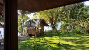 A wooden structure with a sloped roof, surrounded by lush greenery and trees. - Aundanao Oasis Beach (Samal)