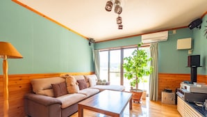 A living room with a sofa, a coffee table, a lamp, a potted plant, and a television. - Share Creative&Bed 'adonoan' (Takeo)