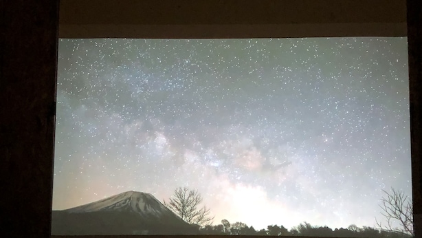 A room with a starry night projection on the wall, a table, and two chairs. - Share Creative&Bed 'adonoan' (Takeo)