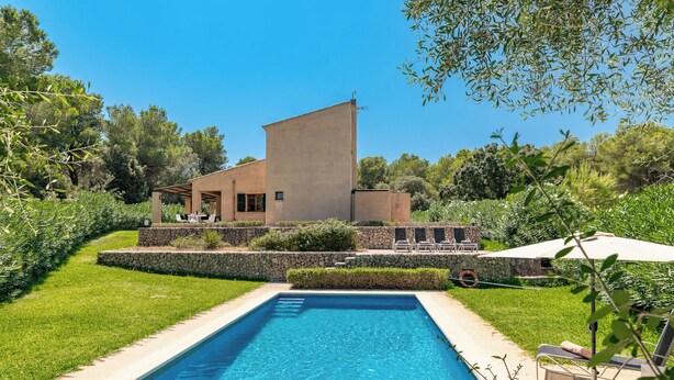 Une maison moderne dotée d’une piscine, de murs en pierre et d’un jardin.