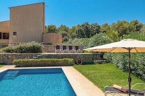 Une piscine avec un mur en pierre et des chaises longues.
