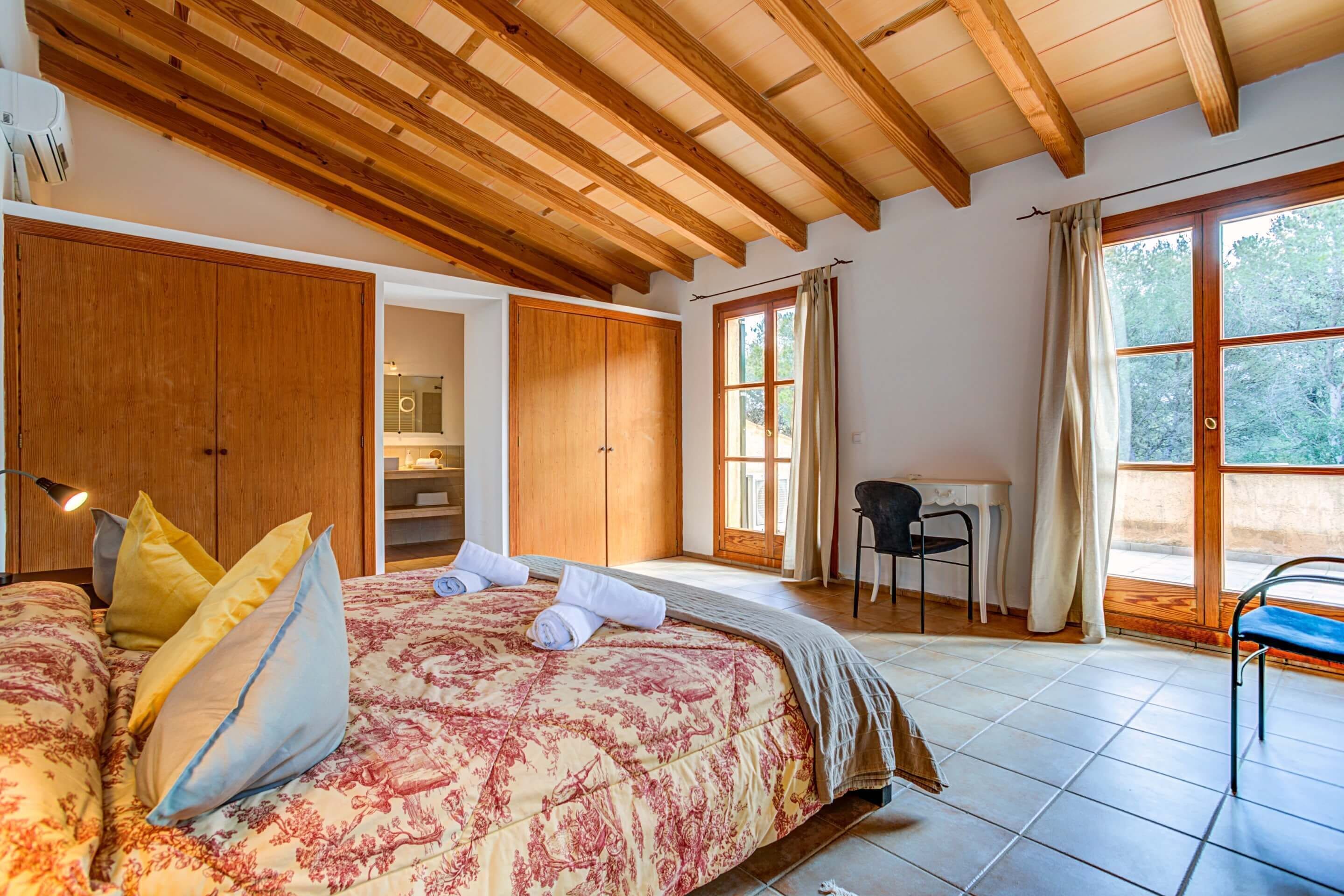 Een slaapkamer met een groot bed, een houten garderobe, een bureau en een stoel.