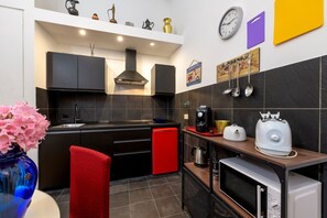 A compact kitchen with modern appliances, a red refrigerator, and a clock on the wall. - Babuino Superior - Spanish steps (Roma)