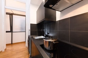 Una cucina moderna con piano cottura, lavello e piastrelle nere.