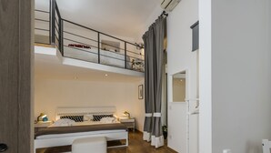 A modern bedroom with a bunk bed, a bedside table with a lamp, a white bench, and a view of the upper bunk. - Babuino Superior - Spanish steps (Roma)