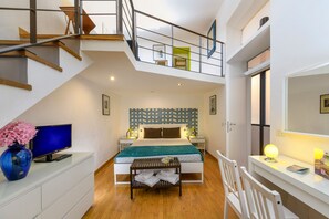 A bedroom with a bed, bedside table, lamp, and a TV on a dresser. - Babuino Superior - Spanish steps (Roma)