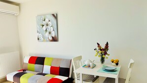 A modern living room with a multi-colored sofa, a dining table with chairs, a vase of flowers, and a painting on the wall. - Sunset paradise in Villefranche (Villefranche-sur-Mer)