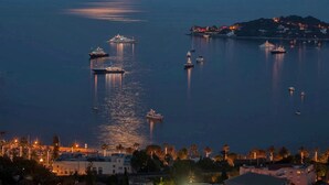 A coastal town at night with boats anchored in the water, a clear moon in the sky, and buildings along the shore. - Sunset paradise in Villefranche (Villefranche-sur-Mer)