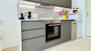 A modern kitchen with grey cabinets, a built-in oven, a microwave, and a sink. - Sunset paradise in Villefranche (Villefranche-sur-Mer)