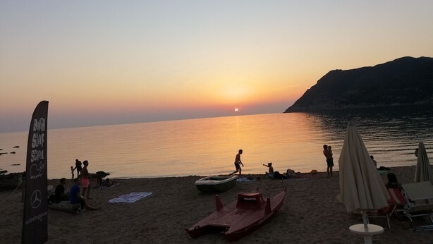 A beach with people, a sunset, and a mountain in the background. - The blue holiday home of La Pervinca (Villassunta)