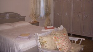 A bedroom with a bed, a nightstand, a chair, a wardrobe, and a chandelier. - The blue holiday home of La Pervinca (Villassunta)