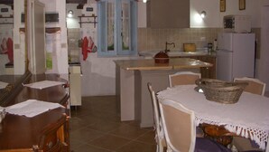 A compact kitchen with a dining area, featuring a central island, a refrigerator, and a sink. - The blue holiday home of La Pervinca (Villassunta)
