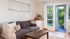 Una sala de estar con un sofá gris, una mesa de centro de madera y un aparador blanco.