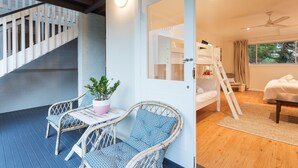 Una habitación con literas, una mesita con sillas, una planta en maceta y una escalera.