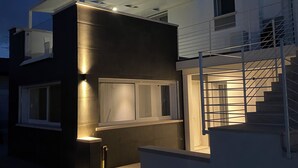A modern two-story house with a glass facade, a staircase, and a well-lit exterior. - Country villa app. with POOL, A/C,WIFI, PARK and 28sqm PRIVATE TERRACE. (Casalserugo)