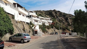 A residential area with white buildings, a road, and a hillside. - Ibiza Bramer 27 Canyelles Roses - Barneda (Rosas / Roses)