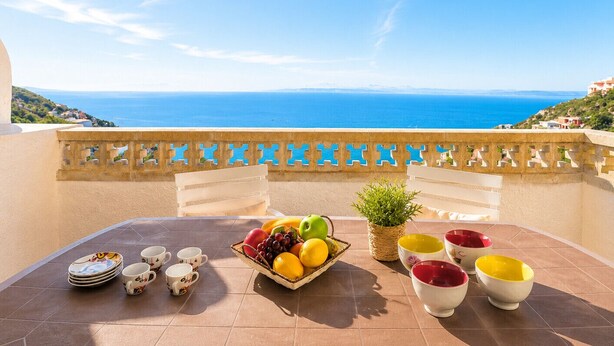 A terrace with a table set for breakfast, a view of the sea, and a decorative railing. - Ibiza Bramer 27 Canyelles Roses - Barneda (Rosas / Roses)