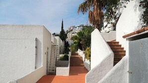 A narrow, white-walled alleyway with a red-tiled path leading to a staircase. - Ibiza Bramer 27 Canyelles Roses - Barneda (Rosas / Roses)