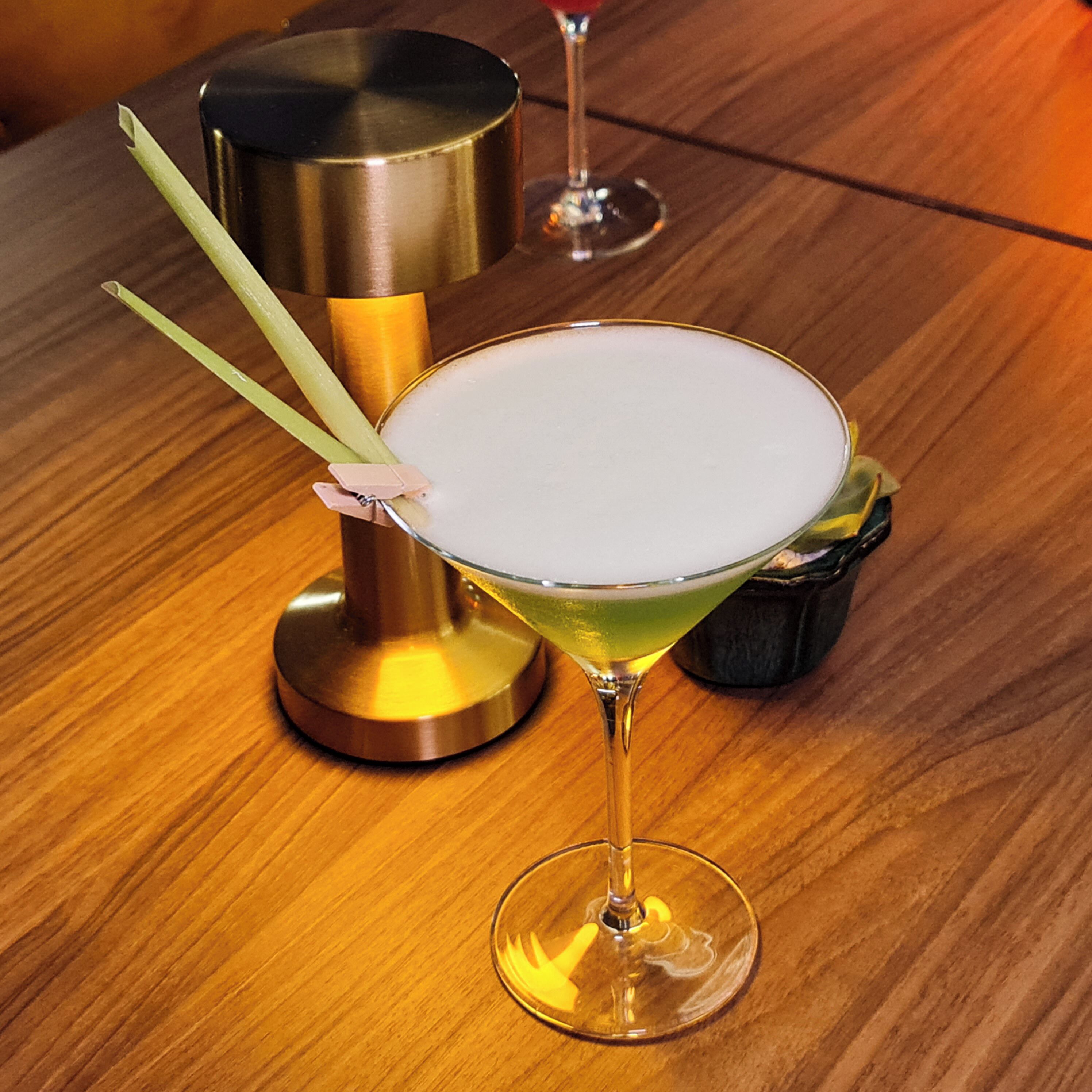 Una copa de martini con espuma sobre una mesa de madera.