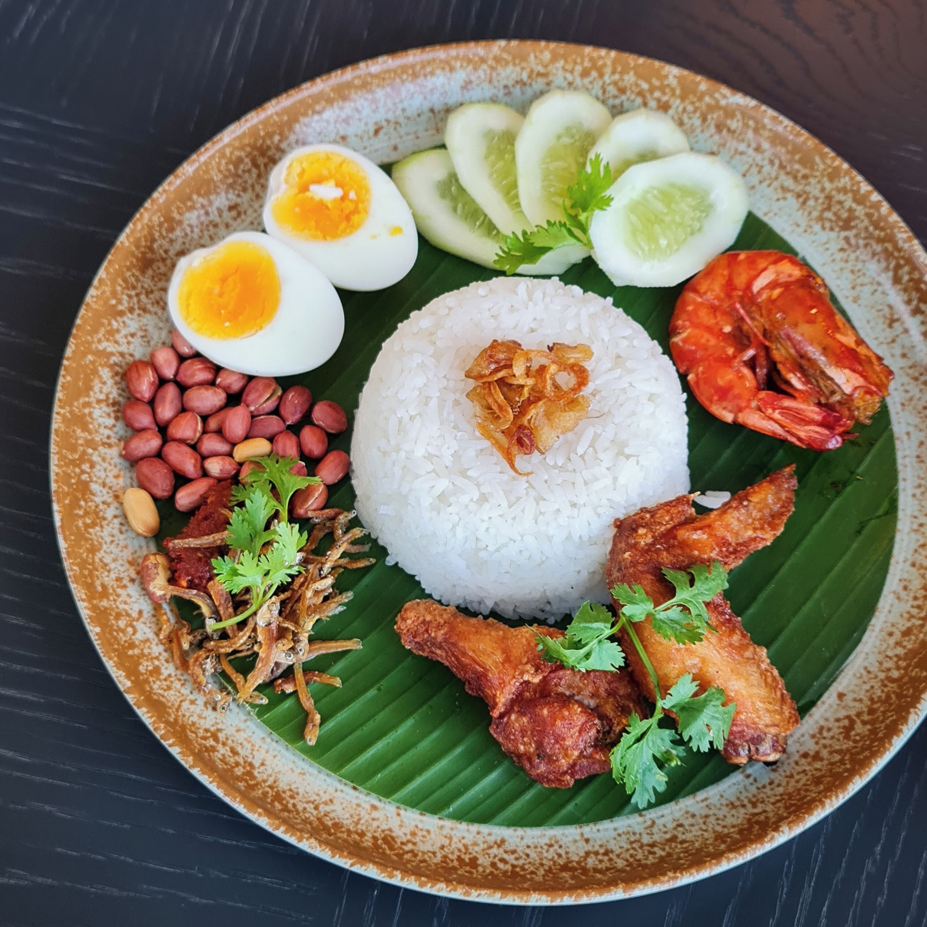 A plate of food with rice, eggs, peanuts, and a variety of vegetables.