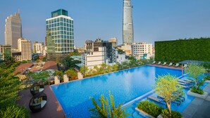 A rooftop pool with lounge chairs, surrounded by modern buildings and a clear sky.