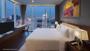 A modern hotel room with a large bed, a desk, and a television. The room has a city view with tall buildings. - Sedona Suites Ho Chi Minh City (Ho Chi Minh City)