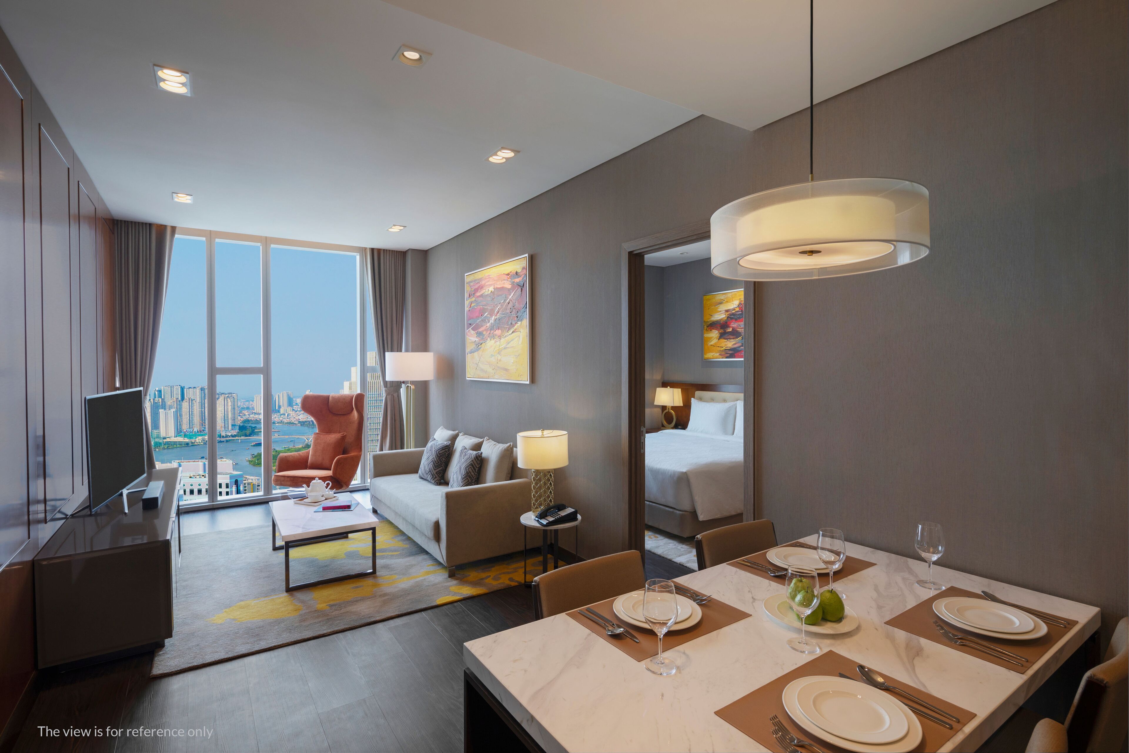 A modern hotel room with a dining area, a sofa, a TV, and a city view.