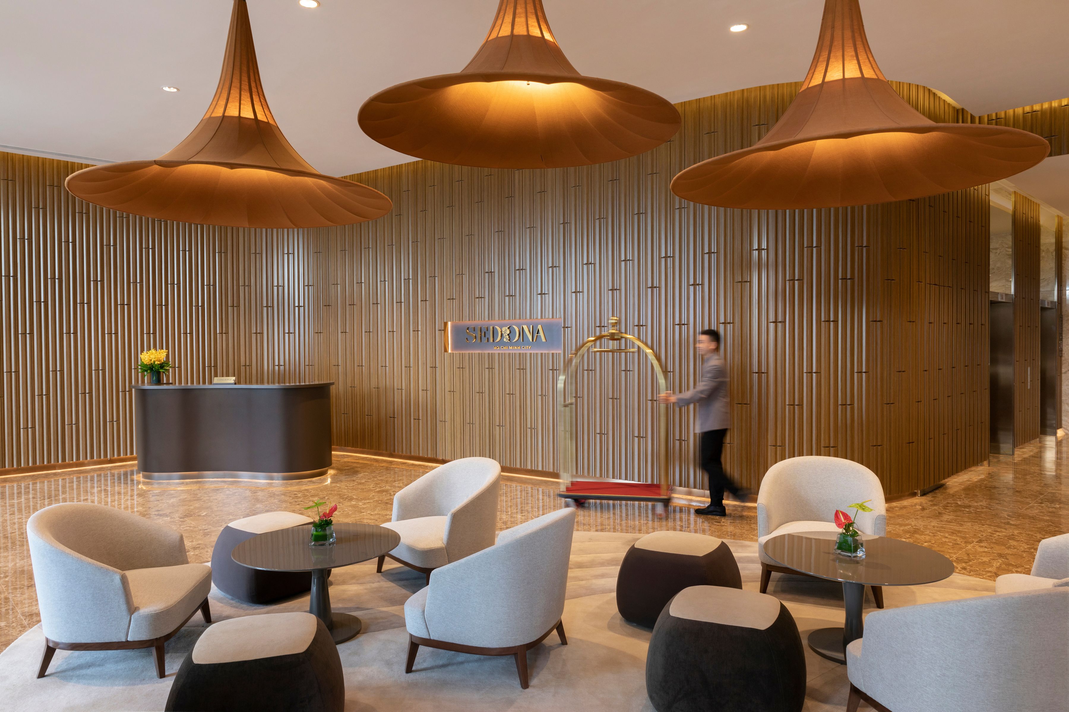 A modern lobby with a reception desk, seating area, and large pendant lights.