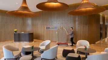 Un lobby moderno con mostrador de recepción, zona de estar e iluminación colgante de gran tamaño.