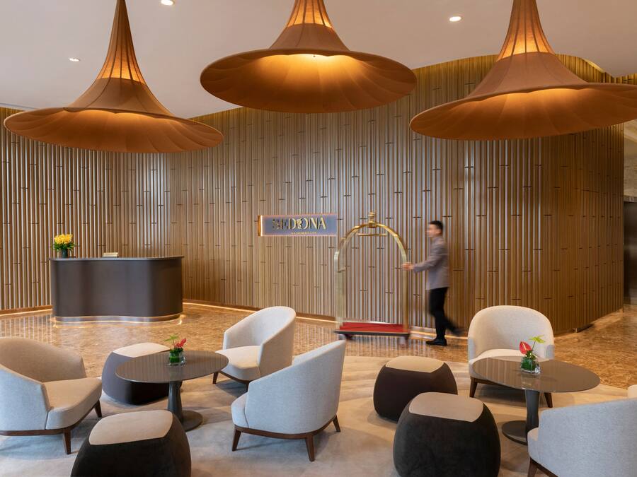 Un lobby moderno con mostrador de recepción, zona de estar e iluminación colgante de gran tamaño.