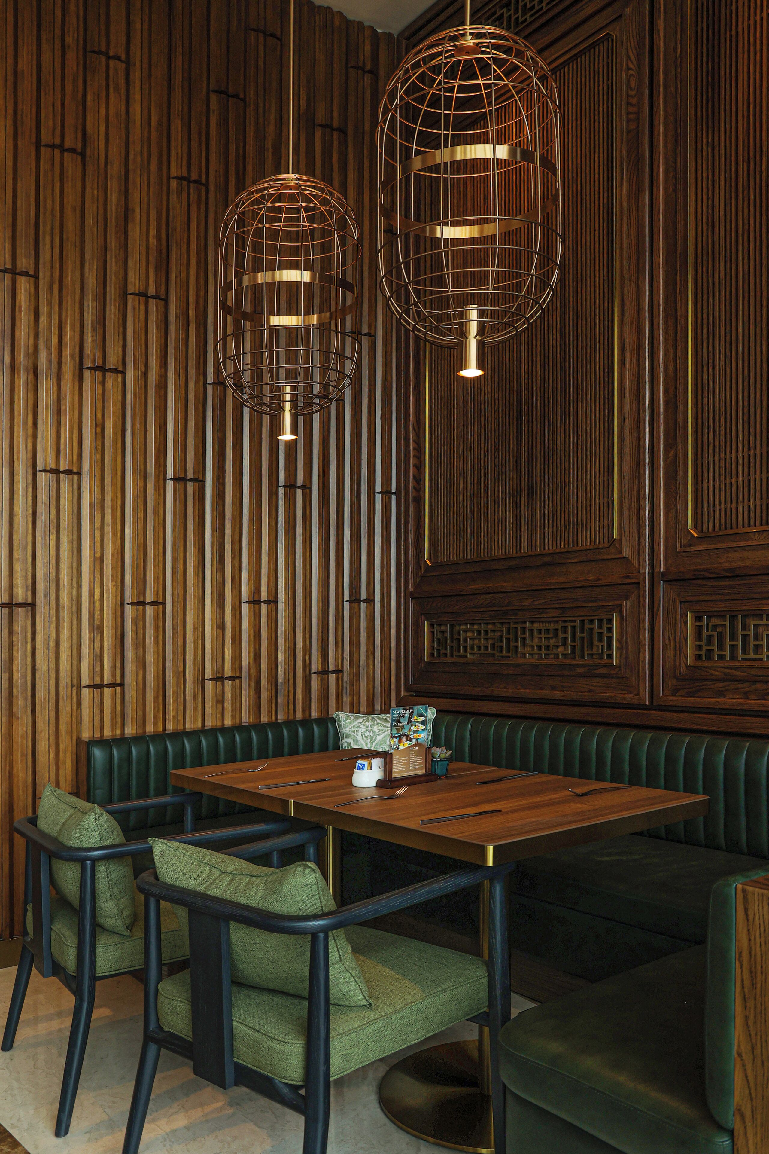 A wooden-paneled room with a green upholstered booth and a wooden table.