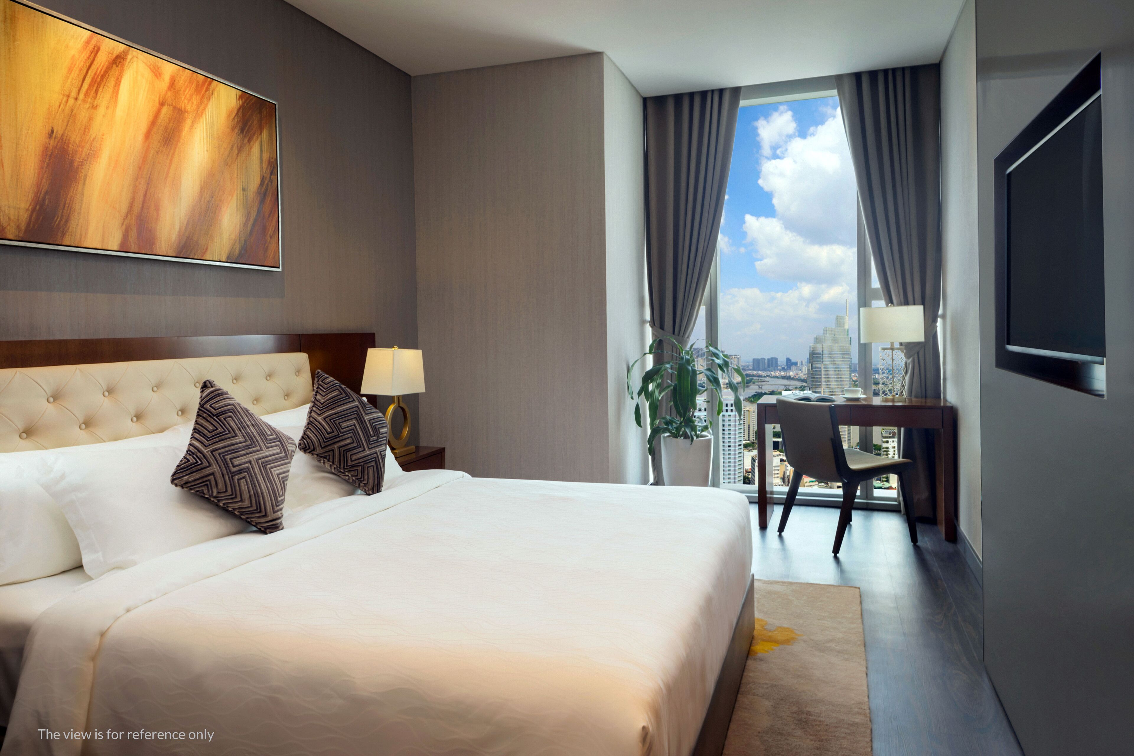 A hotel room with a large bed, a desk, and a view of the city.