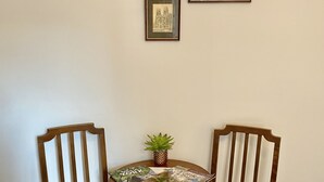 A dining area with two wooden chairs and a small table, a potted plant, and three framed pictures on the wall. - Vikings Accommodation (York)