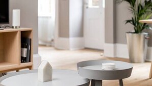 A modern living room with a round table, a white vase, and a bookshelf.