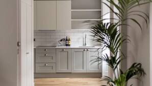 A modern kitchen with white cabinets, a countertop, and a sink.