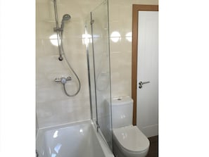 A bathroom with a glass-enclosed shower, a white toilet, and a bathtub.