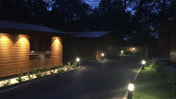 Un sendero que conduce a una edificación de madera con iluminación exterior.