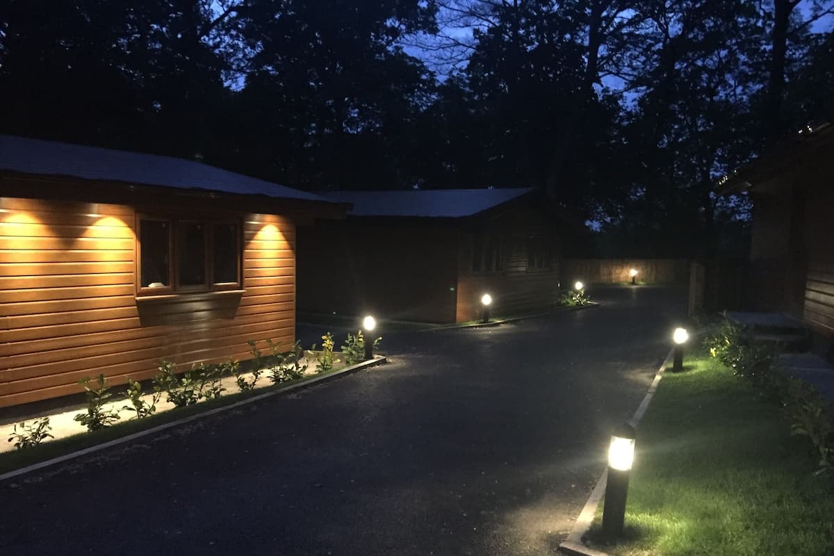 A pathway leading to a wooden building with exterior lighting.
