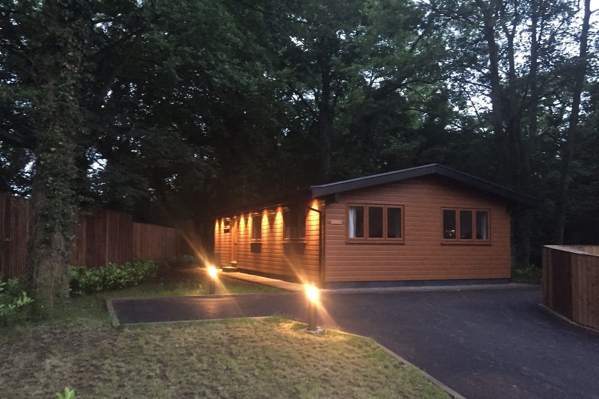 A small wooden cabin with a porch, surrounded by trees.