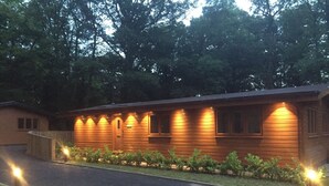 Una cabaña de madera con entrada pavimentada y césped cuidado.