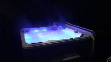 A hot tub with blue lighting, surrounded by darkness.