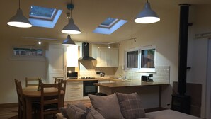 Una sala de estar acogedora con un sofá y una mesa de comedor, una cocina con electrodomésticos modernos y tragaluces.