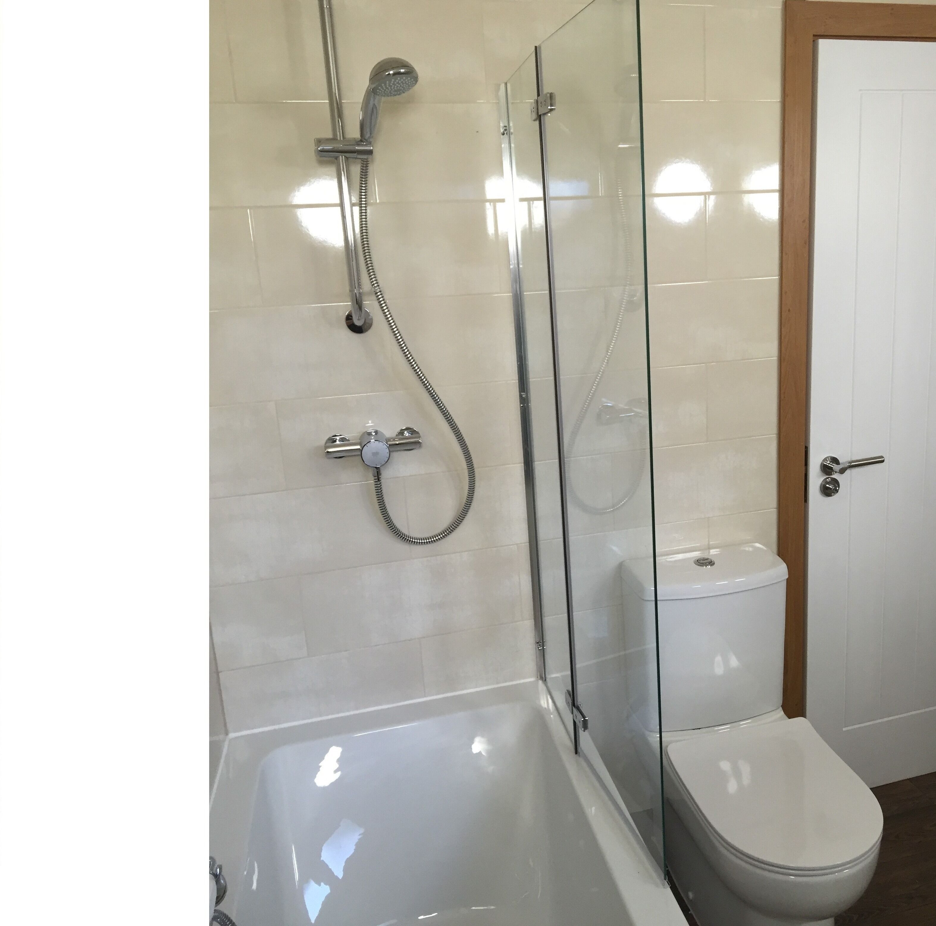 Un baño moderno con ducha de vidrio, bañera blanca y retrete.