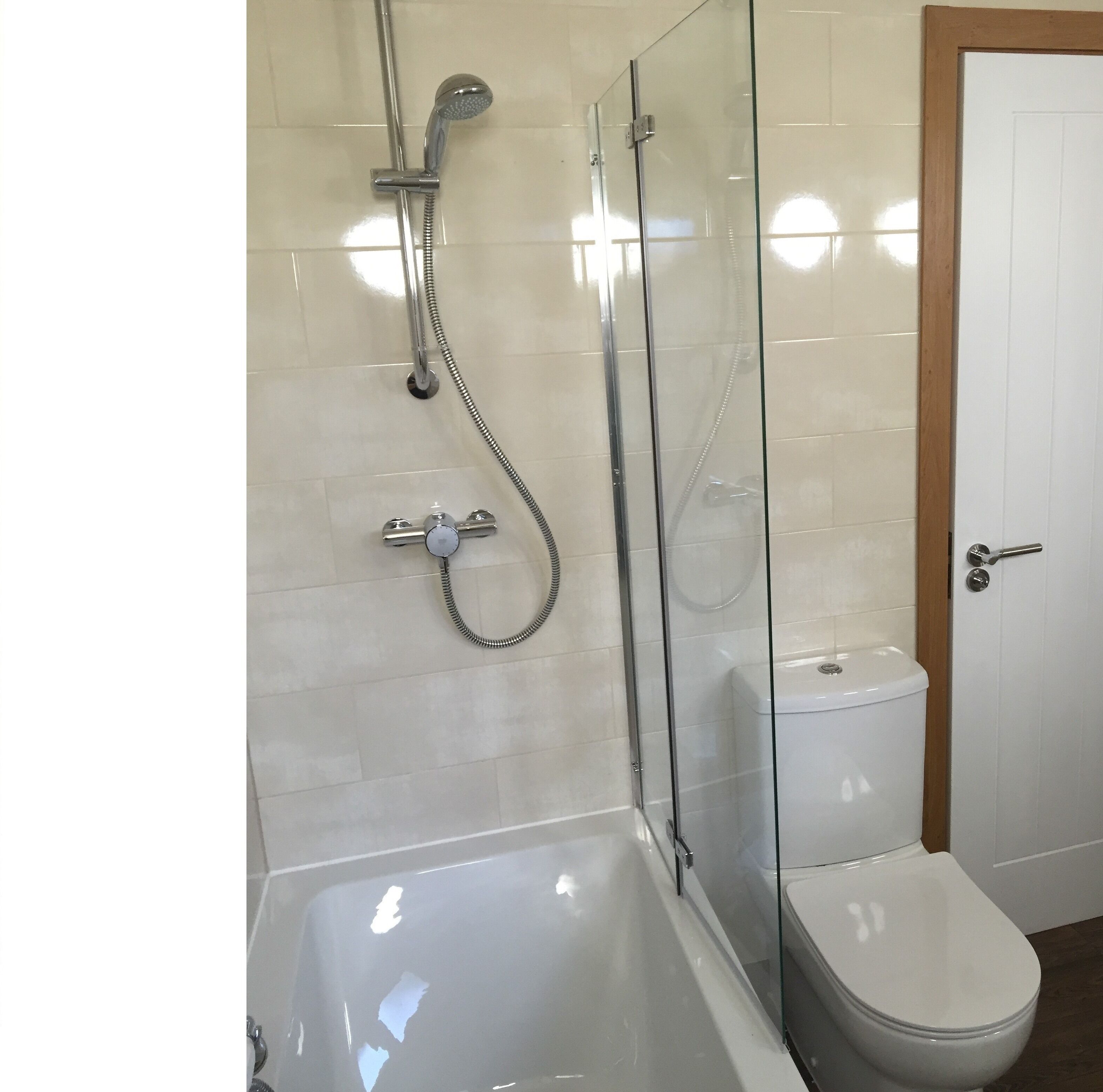 Un baño moderno con ducha de vidrio, inodoro blanco y bañera.