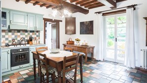 A kitchen with a tiled floor, wooden cabinets, a stove, and a dining table with chairs. - Villa with pool and garden (Città di Castello)