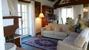 A cozy living room with a sofa, patterned rug, and wooden beams. - Villa with pool and garden (Città di Castello)