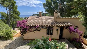 Un petit bâtiment avec un toit en tuiles, une cheminée et une fenêtre avec des volets.