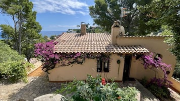 Un pequeño edificio con techo de tejas, chimenea y ventana con contraventanas.