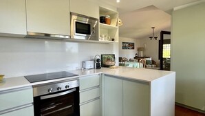 Une cuisine moderne dotée d’un four encastré, d’un micro-ondes et d’un grand îlot central.