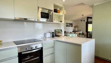 Een moderne keuken met een ingebouwde oven, magnetron en een groot eiland.